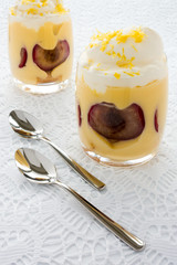 Two Glasses filled with Plum Trifle Dessert on white fabric background.