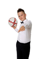 Młody chłopiec w białej koszuli trzyma piłkę na dłoni.