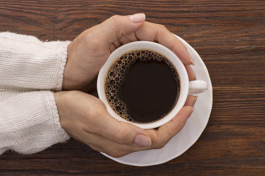 Female hands holding cups of coffee on rustic background