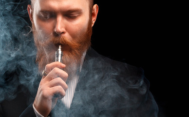 vaping man holding a mod. A cloud of vapor. Black background