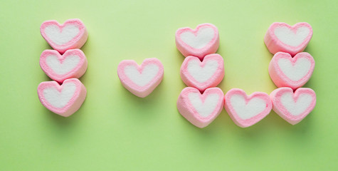Obraz premium Pink heart-shaped marshmallow on green background