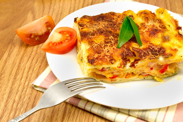 a plate of lasagna on a striped napkin