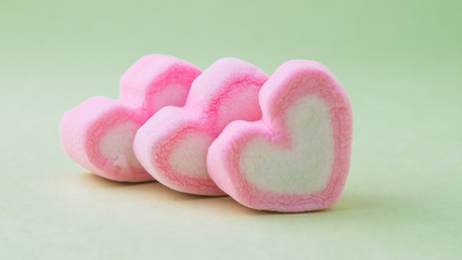 Fototapeta premium Pink heart-shaped marshmallow on green background