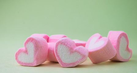 Pink heart-shaped marshmallow  on green background