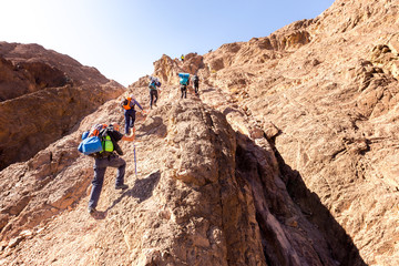 Group backpackers ascending climbing desert mountain trail lifestyle. © subbotsky