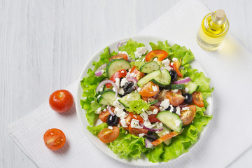 Fresh vegetable Greek salad with oil bottle, top view