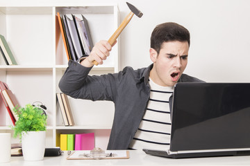 young man with the hammer hitting the laptop computer © carballo