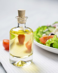 Bottle of olive oil with fresh vegetable Greek salad