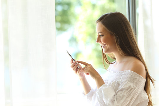 Girl using a phone near a window