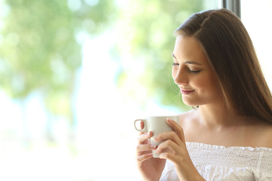 Romantic girl thinking and looking at coffee cup