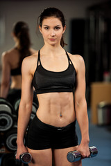 Fototapeta na wymiar Beautiful fit woman works out with dumbbells in a fitness gym