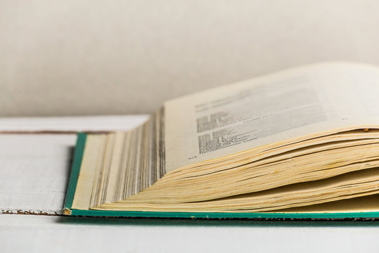 Close up image of open old book on white wooden background. Copy space
