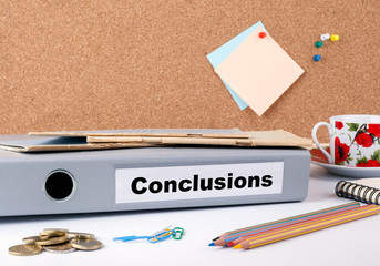 Conclusions. Folder, Coffee Mug, colored pencils on wooden office desk.
