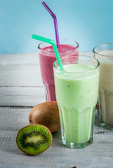 Refreshing milkshakes or smoothies: White (banana), green (apple and kiwi) and berries; with fresh fruits. On a white wooden table, copy space