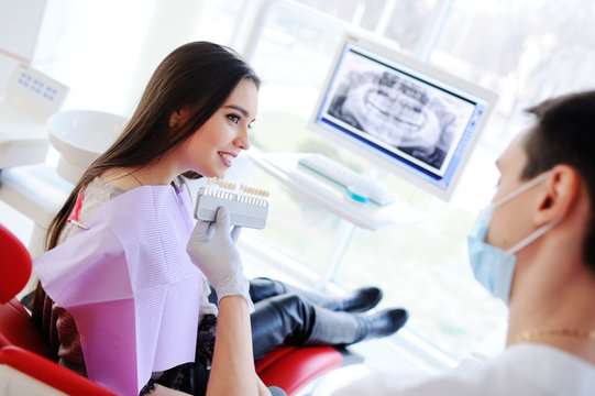 dentist teeth matches the color of the girl against the backdrop of the monitor with X-ray the patient's jaw.