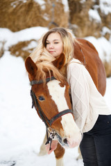 Fototapeta premium Young teenage girl in sweater with horse in winter park