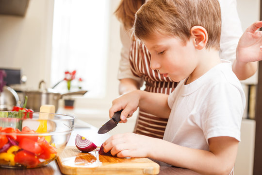 Small boy cooking together with his mother in the kitchen