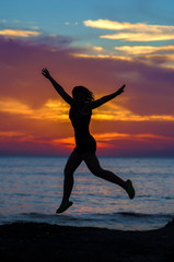 Fototapeta na wymiar silhouette of jumping girl on a background of sea sunset