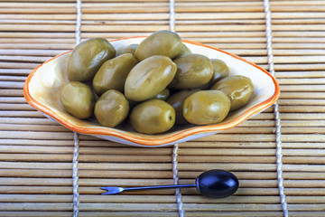 green olives on a plate on a wooden table