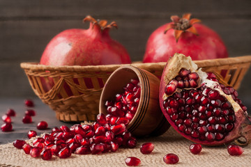 two pomegranate in a wicker basket and grains in the bowl on the old wooden board with sackcloth