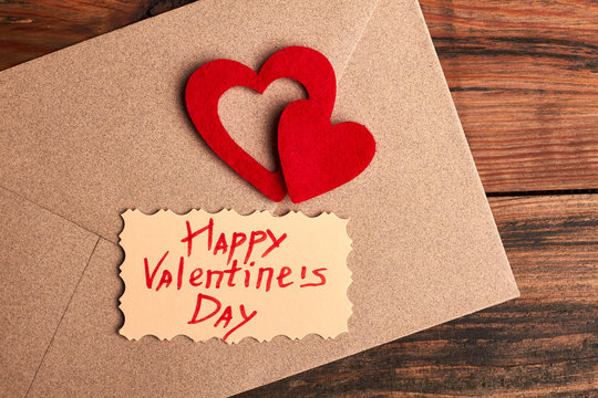 Valentine's Day card on envelope. Red hearts near greeting paper. Send a romantic mail.