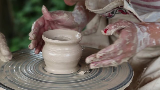 Man and woman makes a pot on pottery wheel. Hands of a potter and his apprentice. Woman is the pupil of a potter. Man and woman hands close up