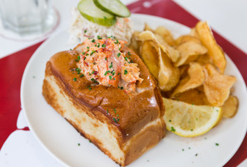 A cheese, prawn, seafood and tomato brioche sandwich, served with crisps and a wedge of lemon.