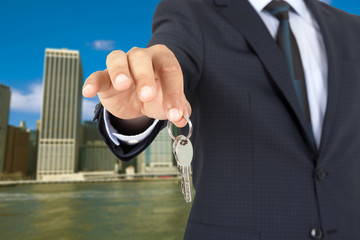 Man in a suit holding a key with city view background