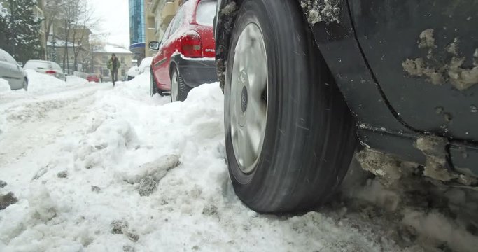 Color footage of a car's wheel being stuck in snow, and spinning.