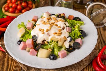 Spicy salad with ham, vegetables and pine nuts