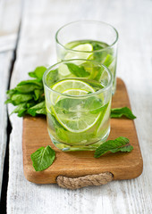 Mojito and ingredients on white wooden surface