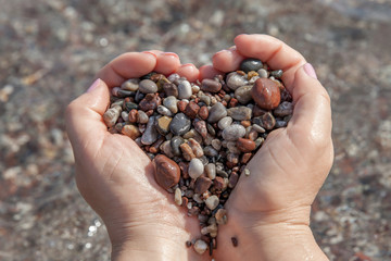Woman hands holding stones in heart shape