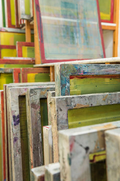 Silk screen printing screens stored in a wooden rack ready for printing.