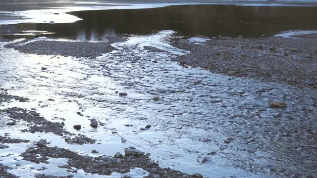 Partially iced river flowing into a mountain lake