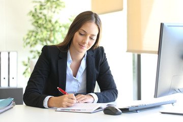 Businesswoman writing in an agenda at office