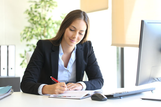 Businesswoman Writing In An Agenda At Office