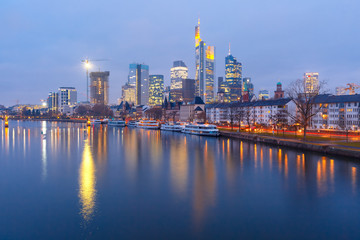 Fototapeta na wymiar Picturesque view of business district with skyscrapers and Old Town witn mirror reflections in the river during morning blue hour, Frankfurt am Main, Germany