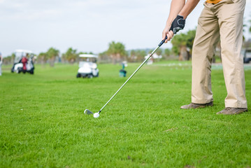 Business man holding golf club playing on grass field background. Active male outdoors
