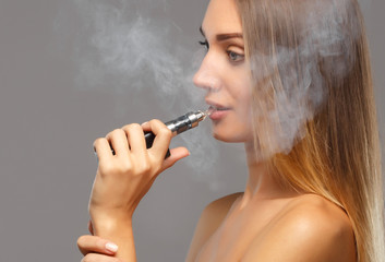 Fototapeta premium Young beautiful woman smoking ( vaping ) e-cigarette