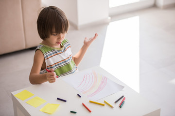 Cute boy drawing at home