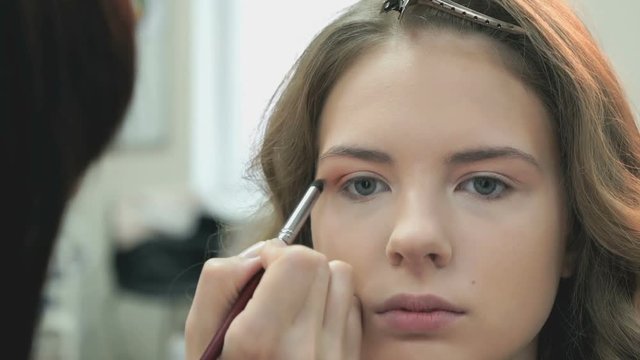 Beautiful bride gets a professional makeup done by the professional makeup artist at the beauty salon