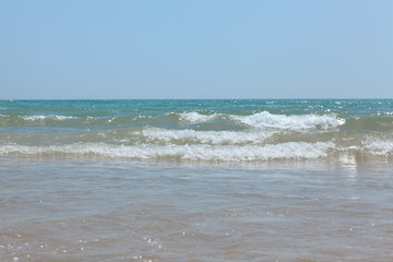 The surging waves of the Mediterranean on the beautiful beach of Valencia in the summer sunny day.