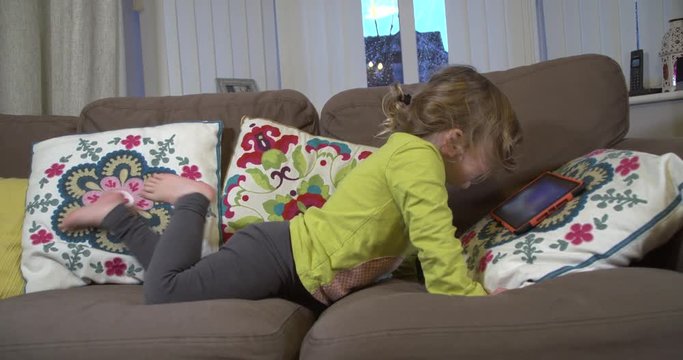 Young girl lying on the sofa chilling out with a digital tablet device
