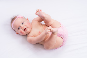 Happy baby girl in pink diaper cover and headband on Valentine's Day