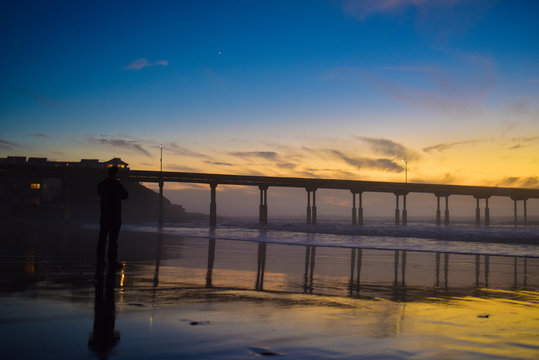 Tourist Taking Picture of Pier at Sunset