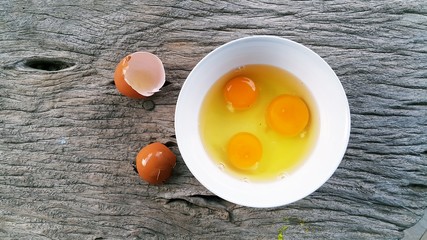 Egg yolks in white bowl on wooden background
