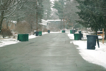 trash bins on both sides of street at trash collecting day in winter