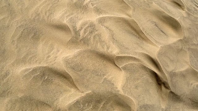 Wind blowing sand grains over sand dunes top view