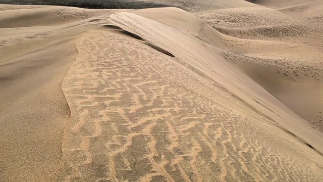 Wind blowing sand grains over sand dunes