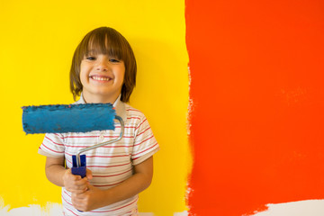 Child painting the home wall in colors